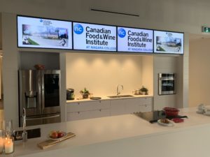 Counter with small kitchen behind and digital signs overhead