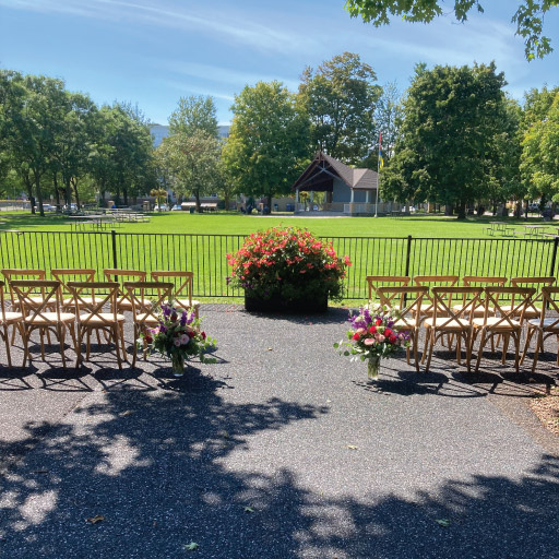 Outside patio prepared for wedding with flowers and rows of chairs on each side at Niagara College Aurora Armoury